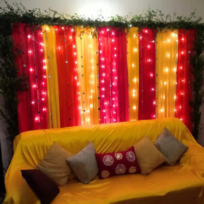 Vibrant Red and Yellow Mehndi Backdrop with Fairy Lights and Greenery Border