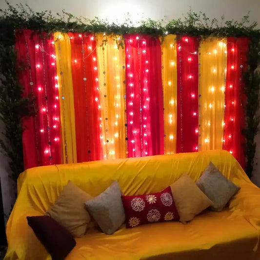Vibrant Red and Yellow Mehndi Backdrop with Fairy Lights and Greenery Border