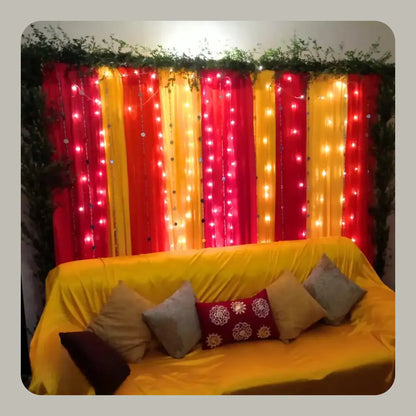 Vibrant Red and Yellow Mehndi Backdrop with Fairy Lights and Greenery Border