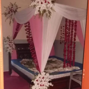 Bridal Bed Decoration with Pink and White Drapes, Red Rose Petal Strands and White Floral Corners