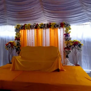 Mehndi Stage with Orange and White Drapes, Floral Frame and Flower Stands